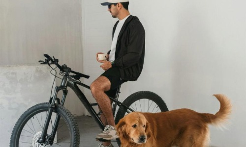 a man sitting on a bike next to a dog